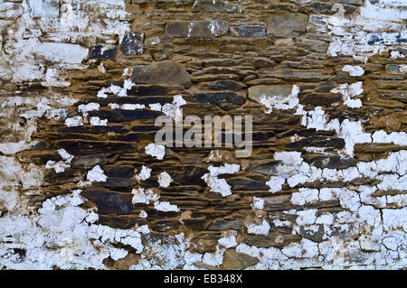 White-wash paint peeling from a weathered handmade stone tiled wall on an ancient Buddhist monastery wall. Stock Photo