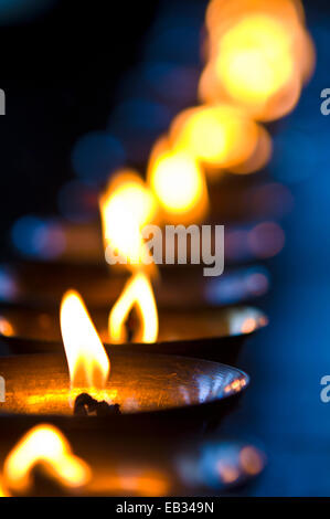 A candle flickers in a brass butter lamp in the prayer room of an ancient Buddhist monastery. Stock Photo