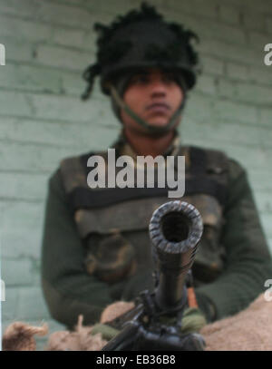 Srinagar, Kashmir. 25th November, 2014. An Indian secuirty police force (CRPF) stands guard out side polling station  the first phase of voting to the Jammu and Kashmir state assembly elections at Rakhi Shalvit , outskirts of Srinagar, Indian controlled Kashmir. Thousands lined up to cast their votes amid a boycott call by Muslim separatist groups who reject India's sovereignty over the disputed Himalayan region. Credit:  sofi suhail/Alamy Live News Stock Photo