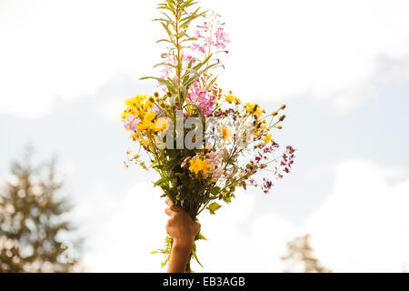Mari boy holding up bouquet of flowers outdoors Stock Photo