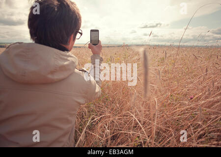 Mari man photographing rural field with cell phone Stock Photo