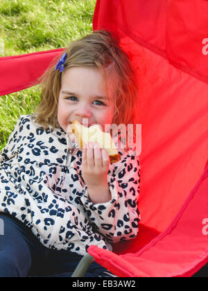 Portrait of smiling girl eating a sandwich Stock Photo