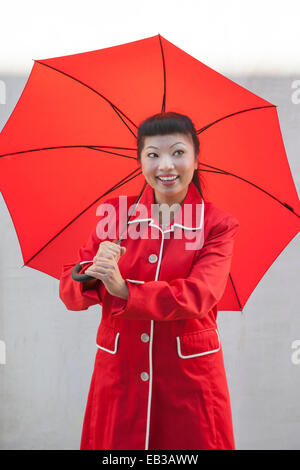 Woman with open umbrella wearing red coat Stock Photo