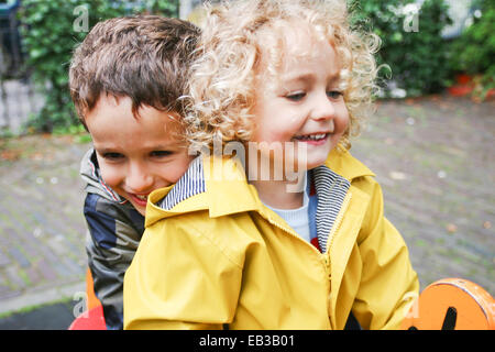 Smiling Boy and girl sitting on spring ride in playground Stock Photo