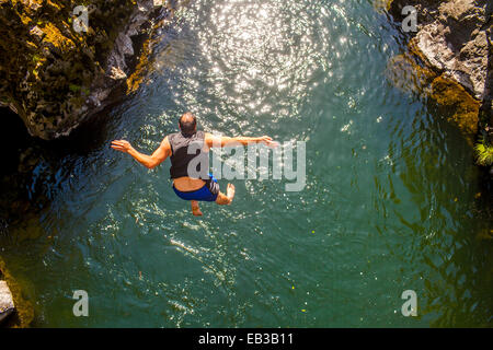 Caucasian man jumping off rocks into ocean Stock Photo