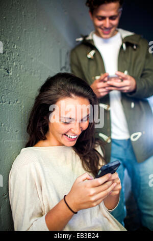 Caucasian couple using cell phones together in tunnel Stock Photo