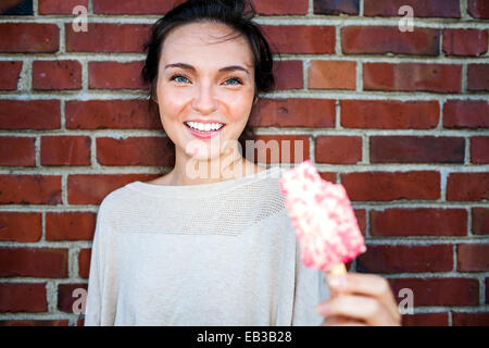 Caucasian woman eating ice cream near red brick wall Stock Photo