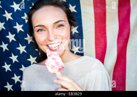 Caucasian woman eating ice cream near American flag Stock Photo