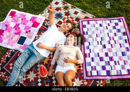 Caucasian couple relaxing on blankets in park Stock Photo