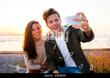 Caucasian couple taking selfie on beach Stock Photo