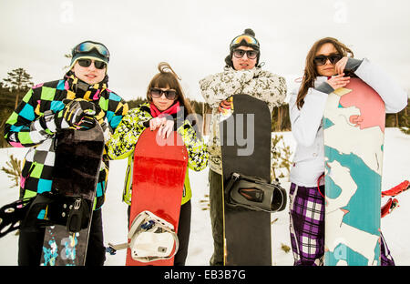 Caucasian couples holding snowboards in snow Stock Photo