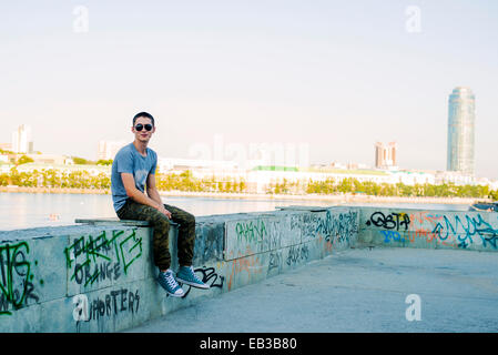 Caucasian man sitting on urban graffiti wall Stock Photo