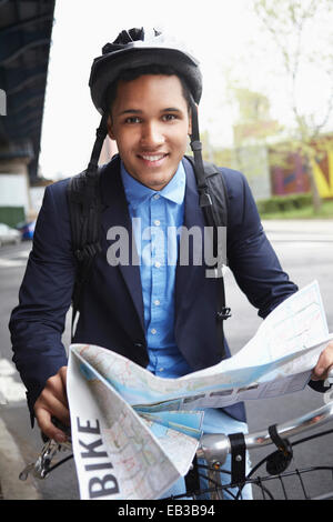 Man on bicycle reading map on city street Stock Photo