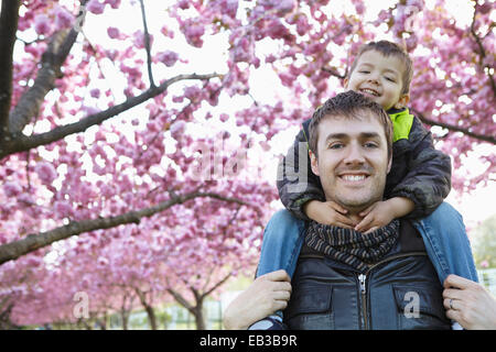 Father carrying son on shoulders in park Stock Photo