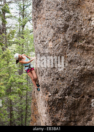 Mixed race girl climbing steep cliff Stock Photo