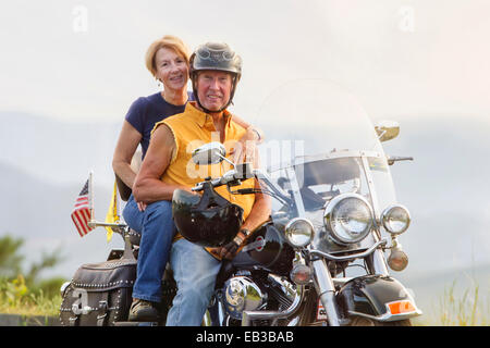 Older Caucasian couple smiling on motorcycle Stock Photo