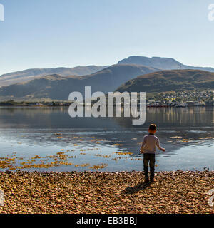 UK, Scotland, Boy (6-7) throwing stones in water Stock Photo