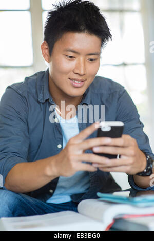 Korean man using cell phone and doing homework Stock Photo