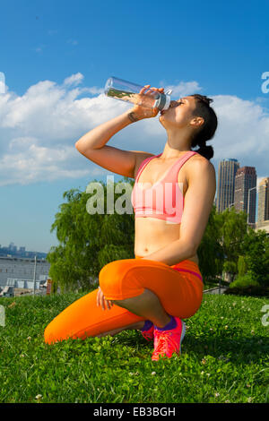 Mixed race woman drinking water in urban park Stock Photo
