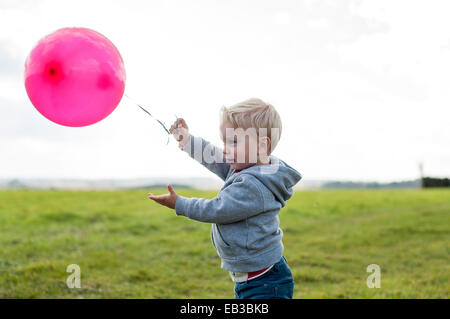 Boy standing in a field holding a balloon Stock Photo