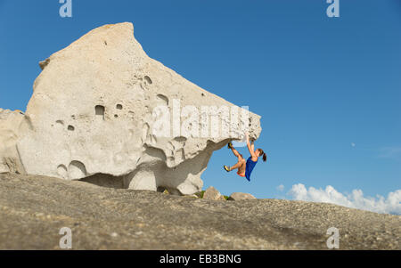 France, Corsica, Woman climbing on big single rock