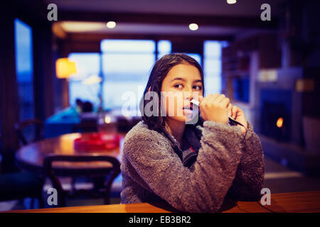 Mixed race girl holding cell phone at table Stock Photo