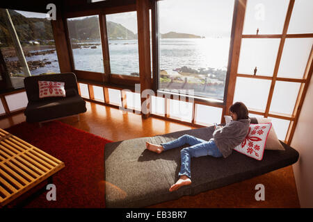 Mixed race girl using cell phone in modern living room Stock Photo