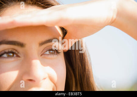 Close up of Caucasian woman shielding eyes from sun Stock Photo
