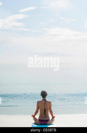 Caucasian woman meditating on beach Stock Photo