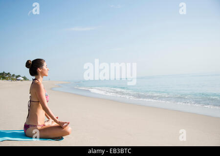 Caucasian woman meditating on beach Stock Photo