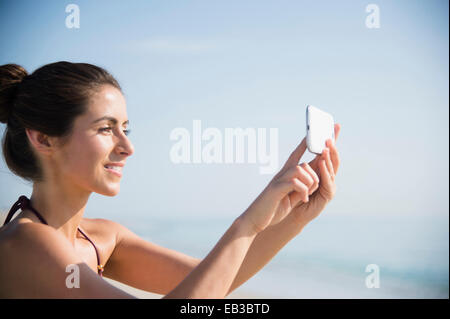 Caucasian woman taking selfie with cell phone at beach Stock Photo