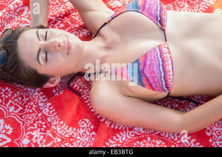 Caucasian woman laying on beach Stock Photo