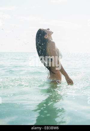 Caucasian woman wading in ocean Stock Photo