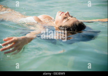 Caucasian woman floating in ocean Stock Photo