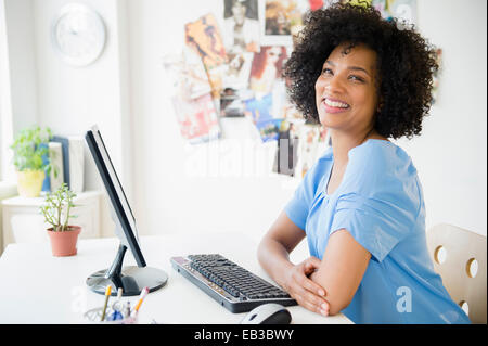 Smiling woman using computer at desk Stock Photo