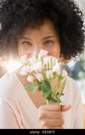 Woman smelling bouquet of roses indoors Stock Photo