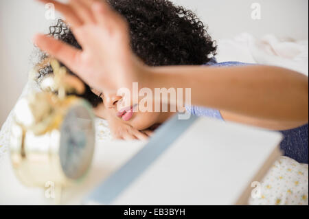 Woman turning off alarm clock in bedroom Stock Photo