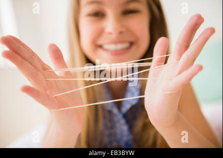 Caucasian girl playing cats cradle game Stock Photo