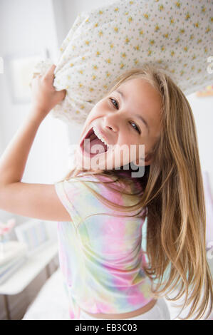 Caucasian girl having pillow fight in bedroom Stock Photo