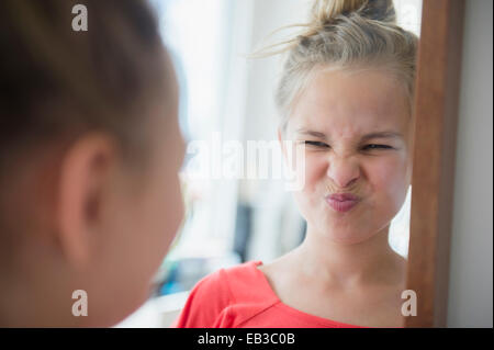 Caucasian girl scrunching up her face in mirror Stock Photo