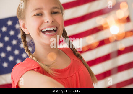 Caucasian girl holding sparkler by American flag Stock Photo