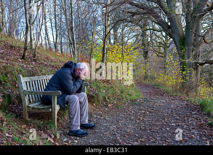 Senior man sitting on bench, with head in hands Stock Photo