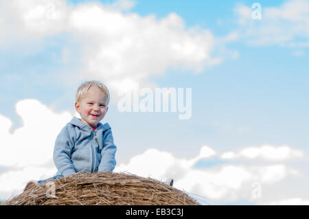 Boy sitting on hay bale Stock Photo