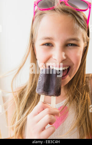 Caucasian girl eating grape popsicle Stock Photo