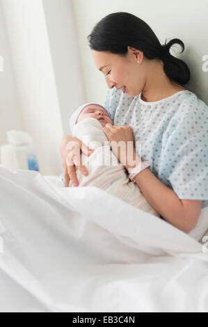 Asian mother holding newborn baby in hospital bed Stock Photo