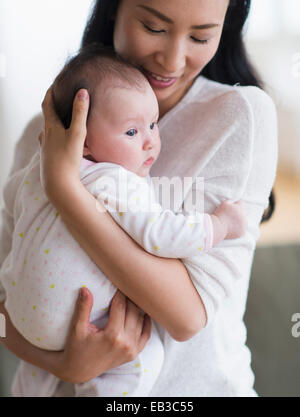 Smiling Asian mother holding baby Stock Photo