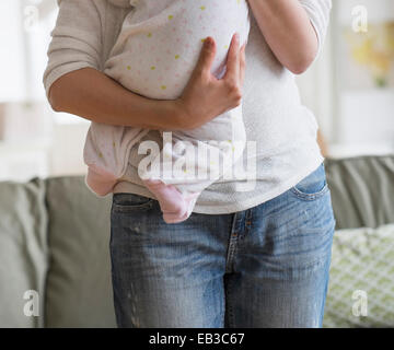 Asian mother holding baby in living room Stock Photo