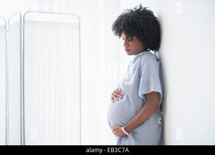 Pregnant African American mother holding stomach in hospital Stock Photo