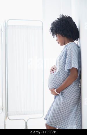 Pregnant African American mother holding stomach in hospital Stock Photo