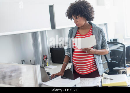 Pregnant African American businesswoman working in office Stock Photo